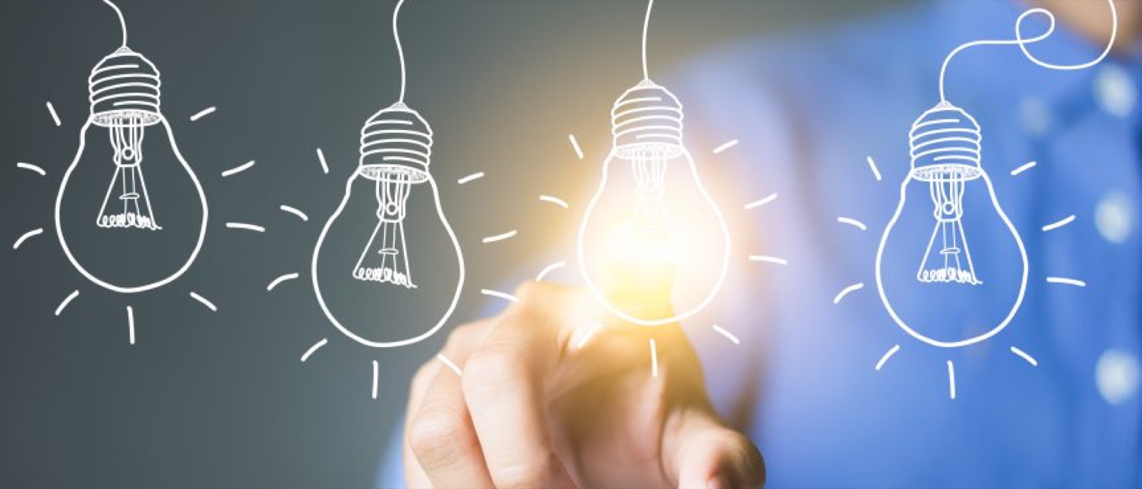 Hand reaching for a lit light bulb among sketched bulbs