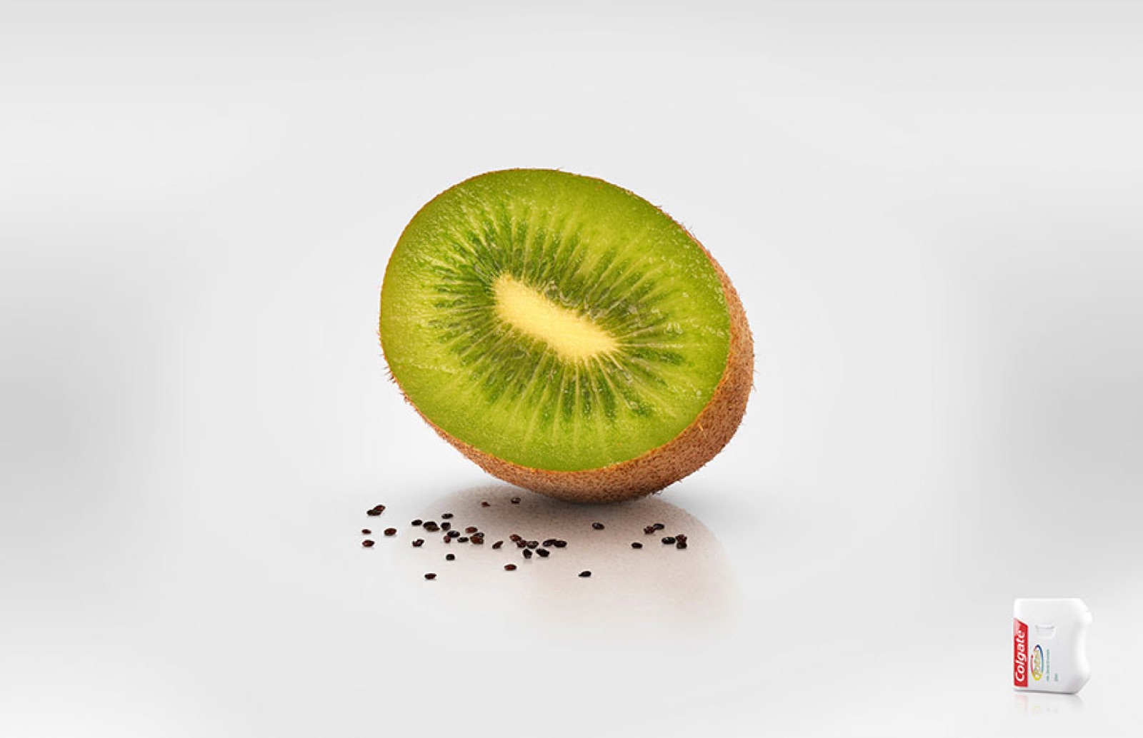 Minimal advert of a halved kiwi fruit with a small juice carton